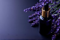 Dark glass bottle with golden dropper cap alongside fresh lavender sprigs on black surface, creating luxurious aromatherapy and wellness composition.