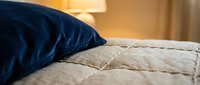 Blue and beige pillows on bed with warm lamp lighting, suitable for home decor, bedroom design, and interior styling projects.