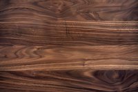 Natural walnut wood texture with rich brown tones and distinctive grain pattern showing organic swirls and lines on wooden surface background.