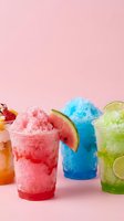 Colorful shaved ice drinks with watermelon, blue raspberry, and lime flavors in clear cups against pink background for beverage, summer, and refreshment designs.