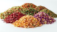 Colorful piles of dried flowers and herbs arranged on white background, including rose petals, chamomile, calendula and lavender buds for tea blends and aromatherapy.