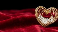Golden wire heart with white pearls on luxurious red velvet fabric for romantic occasions, weddings, Valentine's Day celebrations and love concepts.