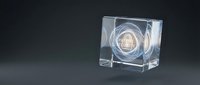 Glowing digital home icon inside transparent glass cube with light rays, representing smart home technology, security systems, and connected living solutions.