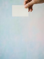 Hand holding blank white card against soft pastel gradient background, suitable for business cards, invitations, marketing materials, and promotional designs.