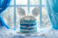 Layered blue and white cake decorated with angel wings on top, set against window with blue curtains and soft winter light, creating magical atmosphere.