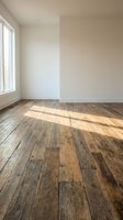 Empty room interior with rustic hardwood floors and natural sunlight streaming through windows creating warm shadows on neutral walls.