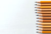 Sharp graphite pencils arranged in diagonal row on white background, creating minimalist composition with copy space for text or design elements.