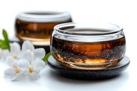 Glass cups with aromatic tea on black coasters decorated with white jasmine flowers. Tranquil zen composition for wellness and relaxation concept.