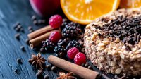 Chocolate dessert with nuts and berries on dark background. Fresh raspberries, blackberries, orange slice, cinnamon sticks and star anise create festive composition.