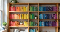 Colorful rainbow bookshelf with organized books arranged by color from red to purple creating vibrant home library display for interior design and organization.