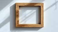 Empty wooden picture frame on white wall with natural window light and shadow overlay creating minimal contemporary composition for art display.