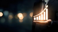 Businessman holding glowing growth chart in palm against dark background with bokeh lights, representing business success and financial progress.