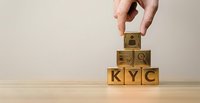Hand placing wooden cube with dollar sign on top of KYC blocks representing know your customer compliance and financial verification process.