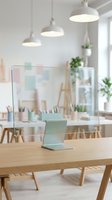 Glass desk divider with mint stand on wooden table in bright Scandinavian classroom with pastel decor and pendant lights.