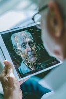 Digital facial recognition scan on tablet screen with biometric data points and neural network overlay showing advanced AI analysis technology.