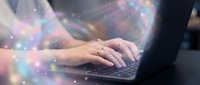 Young Caucasian woman typing on laptop with glowing magical light particles, symbolizing digital creativity, technology, and innovation in modern workspace.