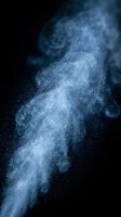 Blue powder explosion cloud with dynamic particles dispersing against dark background for cosmetic and fashion design projects.