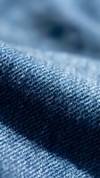 Close-up macro shot of blue denim fabric texture showing detailed weave pattern and fiber structure for fashion and textile design projects.