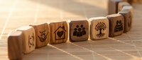 Wooden blocks with environmental and nature icons arranged in row on bamboo mat surface for eco-friendly business and sustainability concepts.