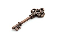 Vintage ornate copper skeleton key with decorative bow design isolated on white background, antique style door key for collectibles and decoration.
