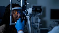 African American female optometrist conducting comprehensive eye examination using advanced diagnostic equipment in modern ophthalmology clinic setting.