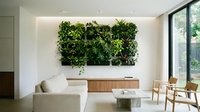 Living room with cream sofa, wooden storage bench, and large living wall of green plants above, natural light from floor-to-ceiling windows, modern minimalist interior design.