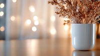 Cozy autumn home decor with dried wheat stems in white ceramic vase on wooden table with warm bokeh lights creating peaceful ambiance for interior design.