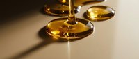 Golden liquid oil drops on white surface, representing skincare serum, cosmetic ingredient, or wellness product for beauty and health applications.