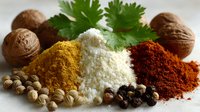 Aromatic spices and herbs with walnuts and coriander leaf, colorful curry, salt, paprika powders and peppercorns arranged on white surface for cooking.