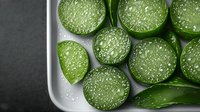 Fresh sliced aloe vera plant with water drops on gray background, top view. Natural organic skincare and wellness concept for cosmetic products.
