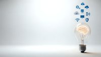 Light bulb with glowing brain and floating technology icons representing artificial intelligence, innovation and digital transformation concepts.