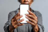 Senior African American woman holding smartphone with blank white screen, mockup for app or website design against gray background.