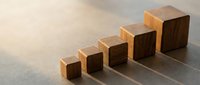 Wooden blocks arranged in ascending height order on neutral surface, representing growth, progress, and business development concepts.