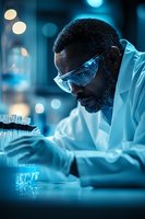African American male scientist in protective eyewear examining test tubes in modern laboratory with dramatic blue lighting and bokeh effects in background.