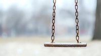 Empty wooden swing with rusty chains against blurred natural background, nostalgic childhood memory concept captured with shallow depth of field.