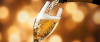 Champagne pouring into flute glass against warm golden bokeh background, celebration and festive occasion beverage.