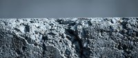 Rough textured concrete surface with deep cracks and weathered appearance for industrial construction and urban decay backgrounds.