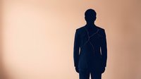 Silhouette of a man in business suit standing against warm beige background, representing corporate professional, leadership, and business concepts for corporate design use.