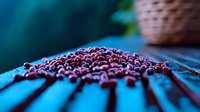 Fresh red cranberries scattered on blue wooden surface with dramatic lighting and shallow depth of field creating moody food photography composition.