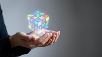 Businessperson holding glowing holographic cube puzzle in palm, representing problem solving, innovation, and digital technology solutions for corporate concepts.