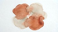 Abstract watercolor paint blobs in warm earth tones creating organic flowing shapes on textured paper background for artistic design projects.