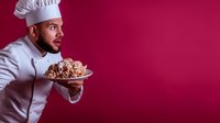 Middle Eastern male chef in white uniform holding plate of appetizing food against burgundy background, expressing excitement and anticipation.