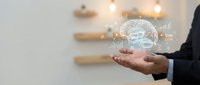 Businessman holding glowing brain hologram with neural network connections in modern office environment for artificial intelligence and innovation concepts.