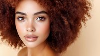 Young African American woman with natural curly afro hair and glowing skin against beige background, beauty portrait showcasing natural makeup and confidence.