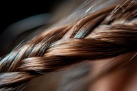 Close-up macro shot of brown braided hair with soft focus and natural lighting, showing intricate weaving pattern and silky texture of feminine hairstyle.