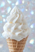 Vanilla soft serve ice cream in waffle cone with pearl decorations against sparkling holographic bokeh background for dessert and summer treat concepts.