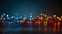 Colorful bokeh lights reflecting on wet surface at night, creating atmospheric urban ambience with blue and orange glowing orbs.