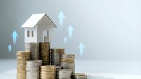 Real estate investment growth concept with miniature house model on stacked coins showing property value appreciation and financial success.