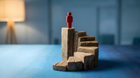 Red figurine standing on wooden staircase blocks, symbolizing career advancement, leadership and business success in modern office environment.
