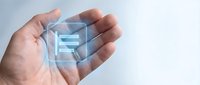 Hand holding holographic digital cube with glowing blue data streams and geometric patterns floating above palm for technology and innovation concepts.